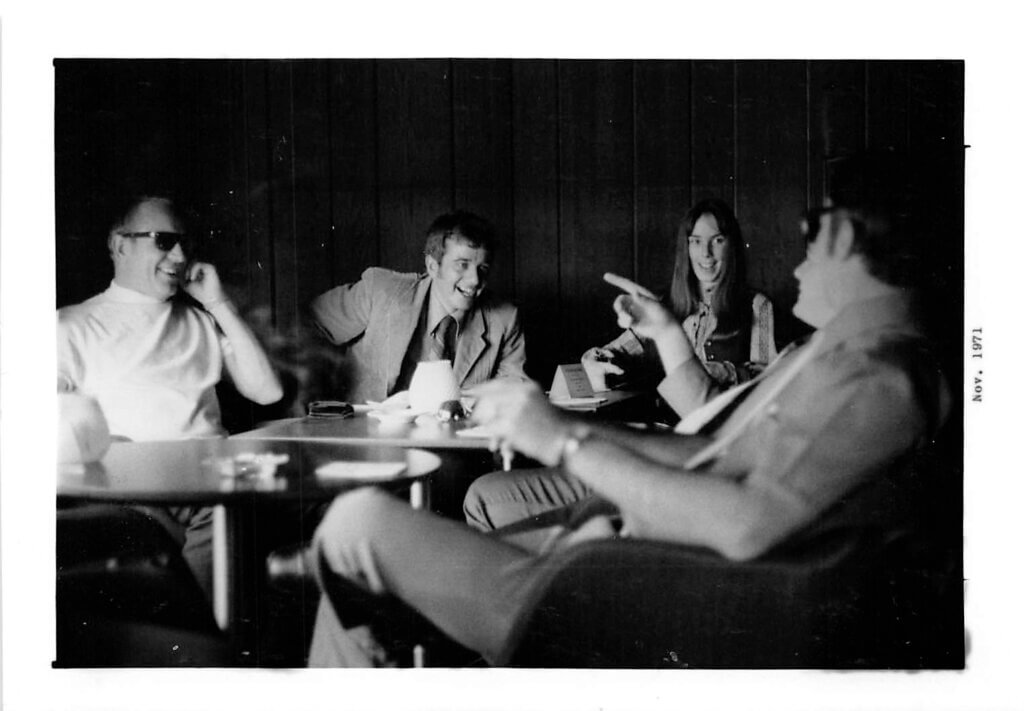 Black and white photo from 1971 showing Chief team members and customers smiling and laughing together during the first loyalty trip to the Bahamas.