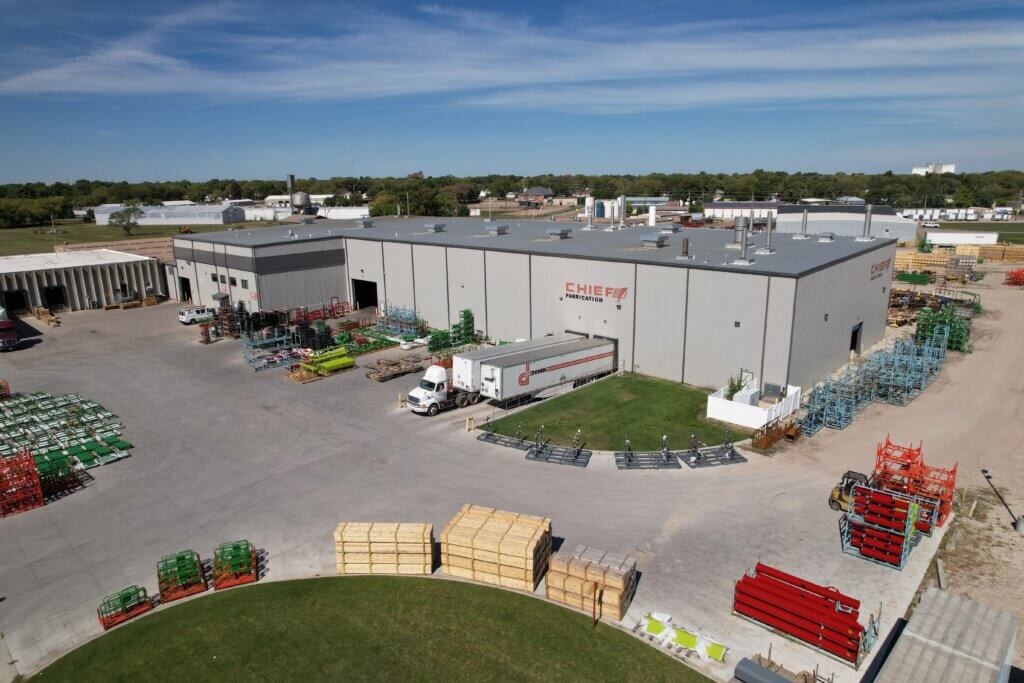 Aerial view of the Chief Fabrication facility with outdoor storage racks, semi-trailers, forklifts, and the Chief Fabrication logo displayed on the building.
