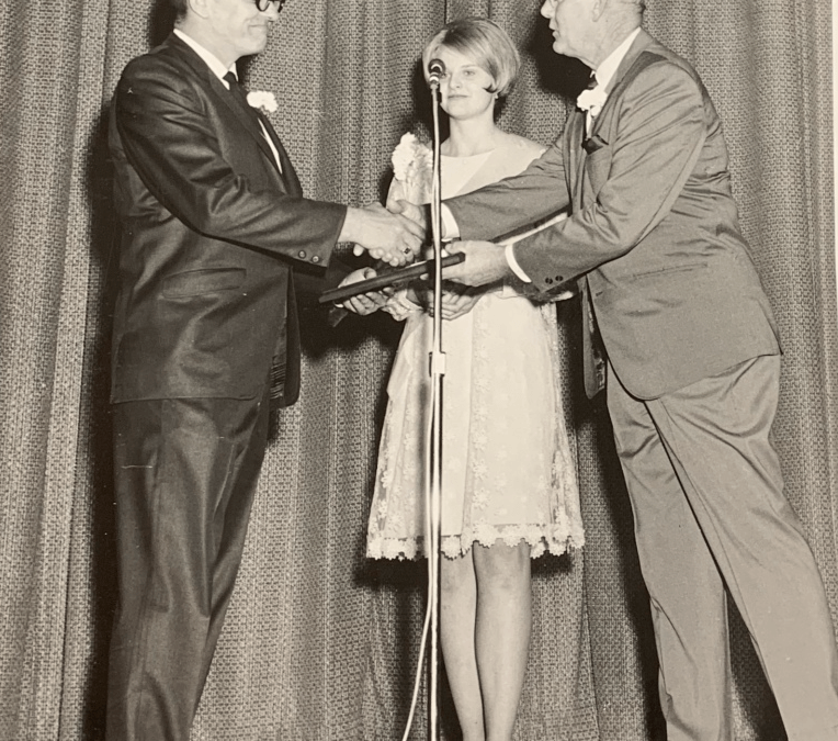 Black and white photo of Virgil Eihusen accepting the Partners in Progress Award from the Grand Island Chamber of Commerce on stage.