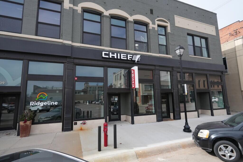 Street-level view of Chief’s modern office storefront in downtown Hastings, Nebraska, featuring the Chief logo above the entrance and neighboring business signage.