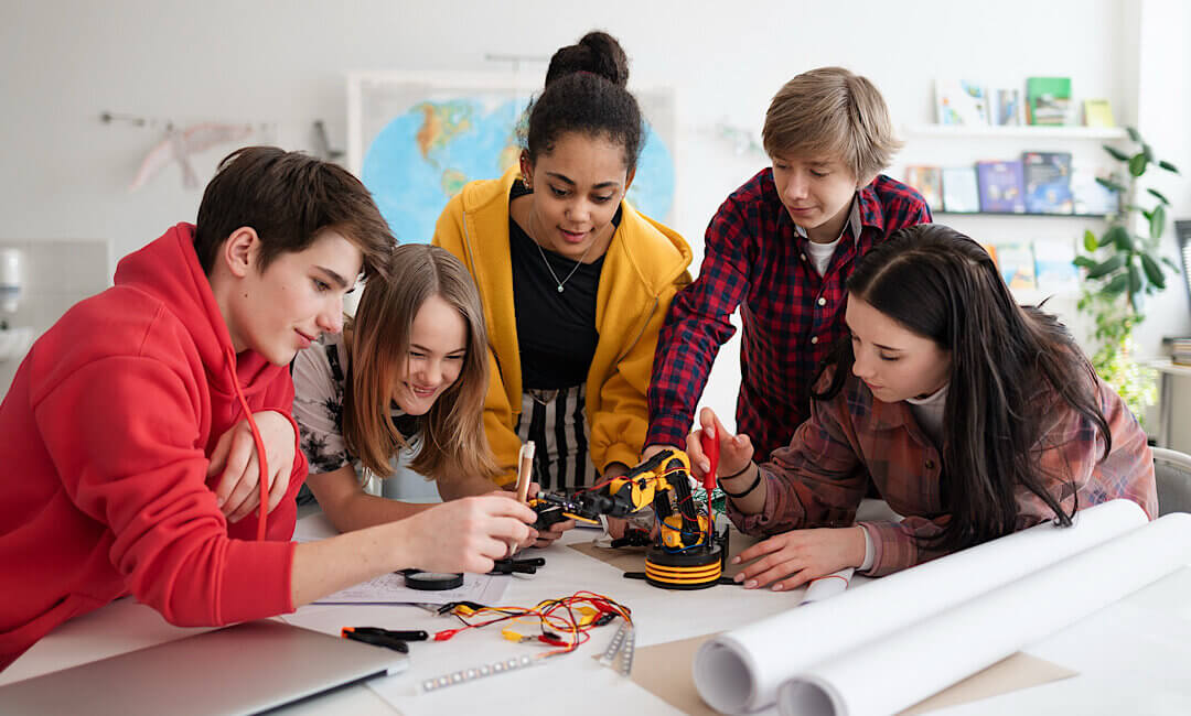 A group of students building and programming electric toys and robots at robotics classroom
