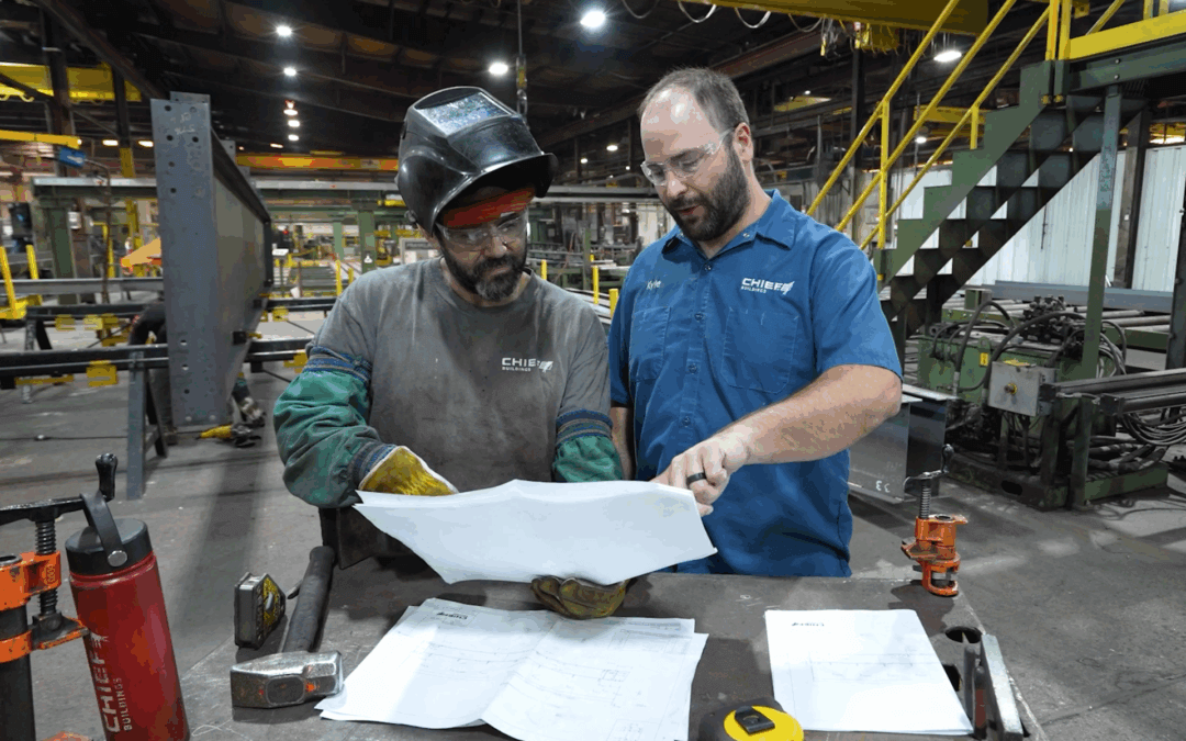 Two Chief Industries employees review a worksheet together inside a Chief Industries manufacturing facility.
